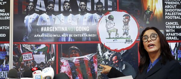 İsrail Kültür ve Spor Bakanı Miri Regev, boykot kampanyasının bir İsrail askerinin topu ayağının altında gasp edip Messi'yi oynatmazken gösterdiği karikatürü ve bir protestocunun kırmızı boya sürülmüş Arjantin formasını yırttığı fotoğraf üzerinden 'terör' suçlamasında bulundu. - Sputnik Türkiye