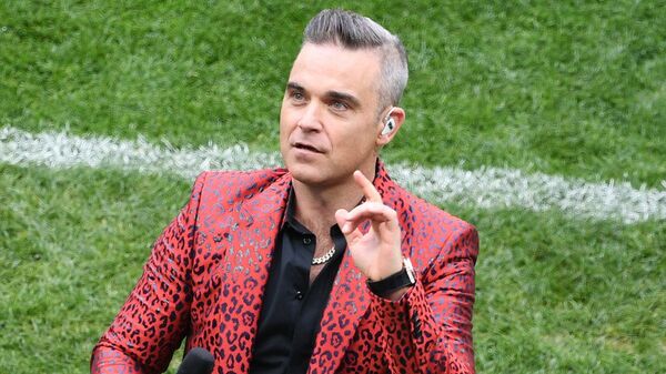Robbie Williams, açılış için geriye sayım yapmak yerine parmağıyla 'bir dakika kaldı' mesajı verdiğini savundu. - Sputnik Türkiye