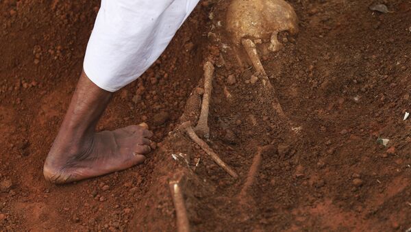 In this Jan 2, 2013 photo, a hospital worker walks by a partially excavated skeleton, at a mass grave found inside the premises of a government hospital in Matale, about 140 kilometers (about 88 miles) north east of Colombo, Sri Lanka. - Sputnik Türkiye