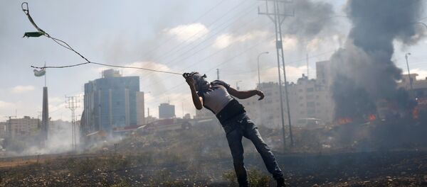 Batı Şeria'daki Ramallah kenti yakınlarında İsrail askerlerine taş atan bir Filistinli - Sputnik Türkiye