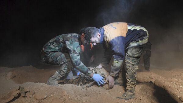 Syrian security forces members remove human remains at the site were discovered two mass graves believed to contain the bodies of civilians and troops killed by the Islamic State militants, in the village of Wawi near the northern city of Raqqa, Syria (File) - Sputnik Türkiye