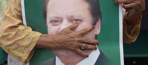 Pakistan'ın yolsuzluktan görevden alınıp hapis cezasına çarptırılan eski Başbakanı Navaz Şerif'in bir posteri ve Şerif'i Lahor'da karşılamak için bekleyen bir destekçisi - Sputnik Türkiye