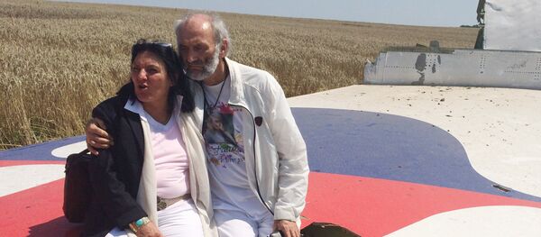 Jerzy Dyczynski and Angela Rudhart-Dyczynski whose daughter, 25-year-old Fatima, was a passenger on Malaysia Airlines flight MH17, sit on part of the wreckage of the crashed aircraft in Hrabove, Ukraine, Saturday, July 26, 2014 - Sputnik Türkiye