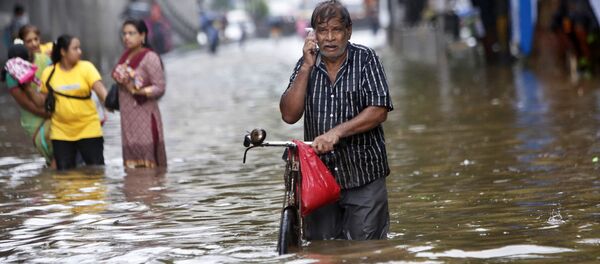 A man talks on his mobile phone while walking though a water logged street during heavy rain in Mumbai, India - Sputnik Türkiye