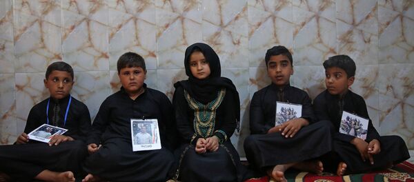 IŞİD tarafından Kerkük otoyolunda kaçırılıp öldürülen Şii erkeklerin Kerbela'daki çocukları, babalarının fotoğraflarını boyunlarına asarak güvenlik güçlerinin üstlerine düşeni yapmasını istiyor. - Sputnik Türkiye
