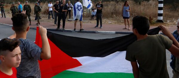 Batı Şeria'daki Rantis kontrol noktasında Tamimi'nin tahliyesini bekleyen Filistinliler, ellerinde bayraklarıyla İsraillilerle karşı karşıya. - Sputnik Türkiye