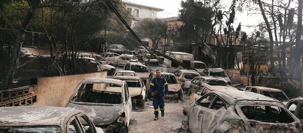 Yunanistan'ın başkenti Atina'nın sahil bölgesi Mati'de yangın felaketinde kavrulan araçlar arasında itfaiye eri - Sputnik Türkiye