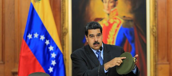 Venezüella Devlet Başkanı Nicolas Maduro saldırıda yaralanan askerlerden birinin şapkasını gösterirken - Sputnik Türkiye