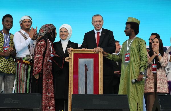 Konuşma sonrası Türkiye'de eğitim gören 25 ülkeden 50 öğrenci platforma davet edildi. Öğrenciler Erdoğan'a Elif harfinin yer aldığı bir tablo hediye etti. - Sputnik Türkiye