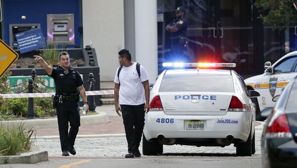 A police officer directs a pedestrian away from a blocked-off area near the scene of a mass shooting at Jacksonville Landing in Jacksonville, Fla., Sunday, Aug. 26, 2018. - Sputnik Türkiye