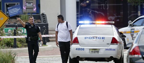A police officer directs a pedestrian away from a blocked-off area near the scene of a mass shooting at Jacksonville Landing in Jacksonville, Fla., Sunday, Aug. 26, 2018. - Sputnik Türkiye