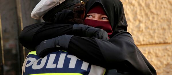 Danimarka'da yürürlüğe giren peçe yasağını protesto eden Ayah adlı eylemciye sarılan kadın polis - Sputnik Türkiye