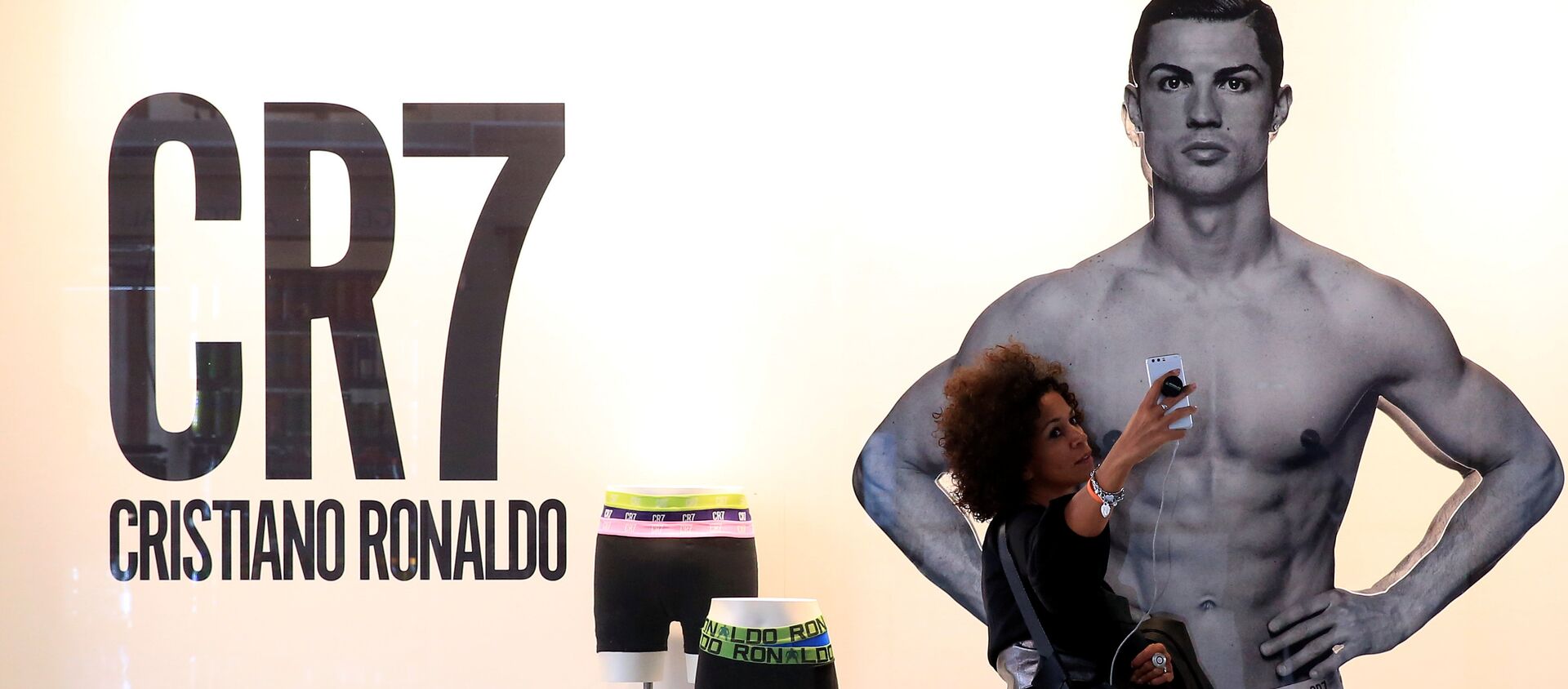 Bu sezon Real Madrid'den Juventus'a transfer olan Cristiano Ronaldo'nun çamaşır reklamının bulunduğu Milano'daki pano önünde bir kadın selfie çekiyor. - Sputnik Türkiye, 1920, 10.10.2018