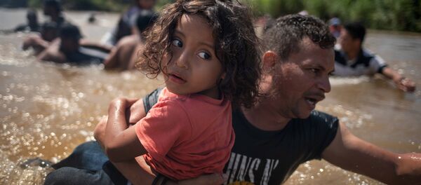 Orta Amerika'dan göçmenler, kafileler halinde Meksika'ya yöneliyor ve ABD'ye doğru ilerliyor. 29 Ekim 2018'de Suchiate Nehri'nin tehlikeki sularından çocuklarıyla birlikte geçen göçmenler, Guatemala'dan Meksika'ya giriş yaptı. - Sputnik Türkiye