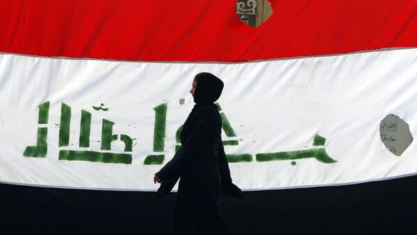 An Iraqi woman walks her national flag during a celebration marking the the departure of US troops from Iraq in Baghdad's Adhamiyah neighbourhood. File photo - Sputnik Türkiye
