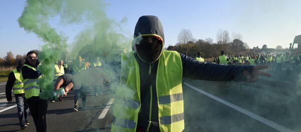 A man holds a flare as demonstrators wearing yellow vests (Gilets jaunes) protest against the rising of the fuel and oil prices on November 17, 2018 in Haulchien near Valenciennes, northern France. - Sputnik Türkiye