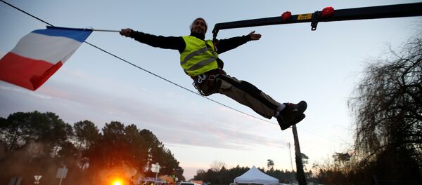 Sarı Yelekler Fransa'nın Cissac-Medoc bölgesinde bir kavşağı işgal edip kontrol noktası kurarken, içlerinden biri vinçten sarkarak elindeki Fransa bayrağıyla  araçları selamladı. - Sputnik Türkiye