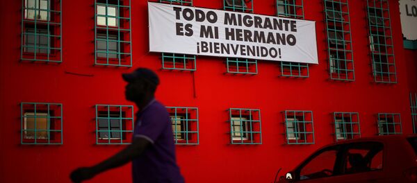 Şili'de Haitili bir göçmen ve Tüm göçmenler kardeşimizdir, Hoşgeldiniz yazılı bir pankart - Sputnik Türkiye