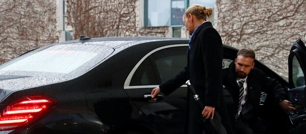 Merkel'in şaşkın bakışları arasında biri kadın biri erkek iki yardımcı kapıyı açabilmek için kolu çekiştirip düğmeleri kurcaladı. Kısa bir uğraşının ardından kapı açıldı ve May dışarı çıktı. - Sputnik Türkiye