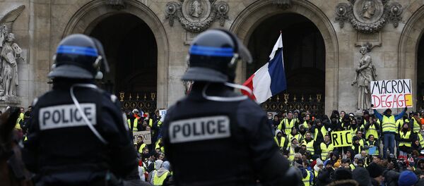 15 Aralık'ta Paris'teki Opera binası önünde atlı polislerin kuşattığı Sarı Yelekler'den biri, Fransa Cumhurbaşkanı Emmanuel Macron'a hitaben Defol git yazılı dövizi havaya kaldırmış halde görülüyor. - Sputnik Türkiye