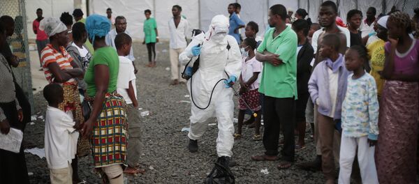 In this file photo daetd Tuesday, Sept. 30, 2014, a medical worker sprays people being discharged from the Island Clinic Ebola treatment center in Monrovia, Liberia - Sputnik Türkiye