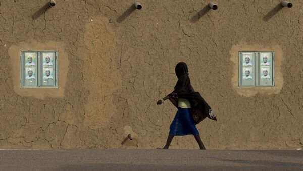 A girl walks past campaign posters on the windows of a mud brick house in Gao, Mali - Sputnik Türkiye