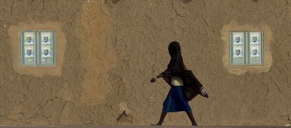 A girl walks past campaign posters on the windows of a mud brick house in Gao, Mali - Sputnik Türkiye