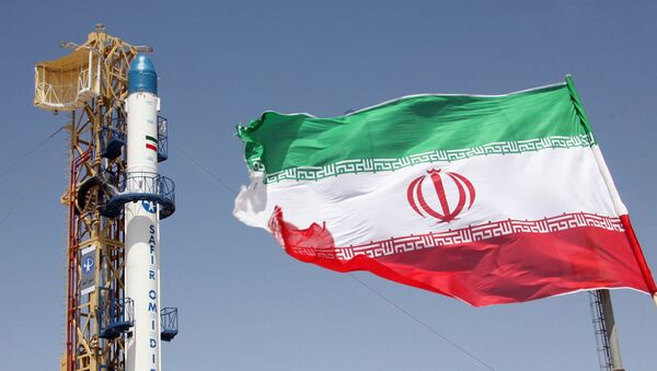 Iranian flag fluttering in front of Iran's Safir Omid rocket, which is capable of carrying a satellite into orbit, before it's launch in a space station at an undisclosed location in the Islamic republic - Sputnik Türkiye
