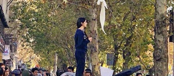İran'da Vida Movahed'in 27 Aralık 2017'de başkenti Tahran'ın Enghelab (İnkılap) Sokağı'nda bir telekom kutusunun üzerine çıkıp beyaz başörtüsünü bağladığı sopayı bayrak gibi sallaması, kadınların örtünmeyi zorunlu kılan yasaya yönelik protestolarının simgesi haline geldi. - Sputnik Türkiye