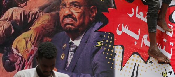 Sudan'da bir gösterici devrik lider Ömer Beşir'in posterinin önünde duruyor - Sputnik Türkiye