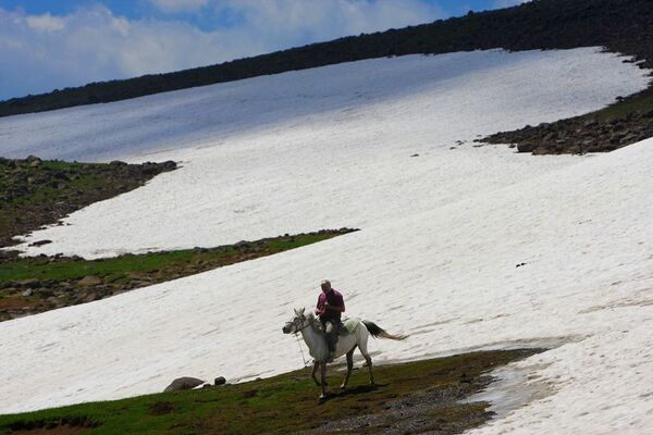 Hınıs’ın Mutluca Yaylası’nda bir köylü, kar üstünde atıyla yayla evine gitmeye çalışıyor. - Sputnik Türkiye