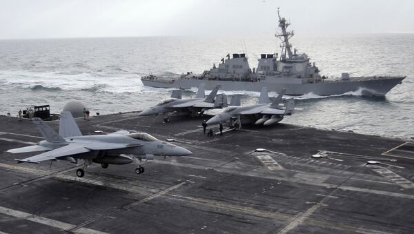 This file photo taken on Monday, Feb. 13, 2012 shows a U.S. F-18 fighter jet, left, land on the Nimitz-class aircraft carrier USS Abraham Lincoln (CVN 72) as a U.S. destroyer sells on alongside during fly exercises in the Persian Gulf - Sputnik Türkiye