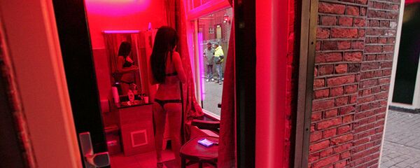 Amsterdam'ın Red Light bölgesinde bir seks işçisi vitrin gibi kullanılan pencerenin gerisinden kendini sergileyerek müşteri bekliyor. - Sputnik Türkiye