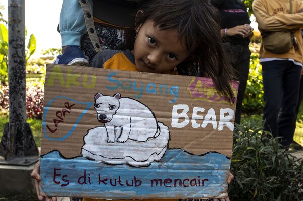 Küresel İklim Grevi'ne katılan Endonezyalı bir kız, buzulların erimesini aç bir kutup ayısını resmeden bir pankartla protesto etti.  - Sputnik Türkiye