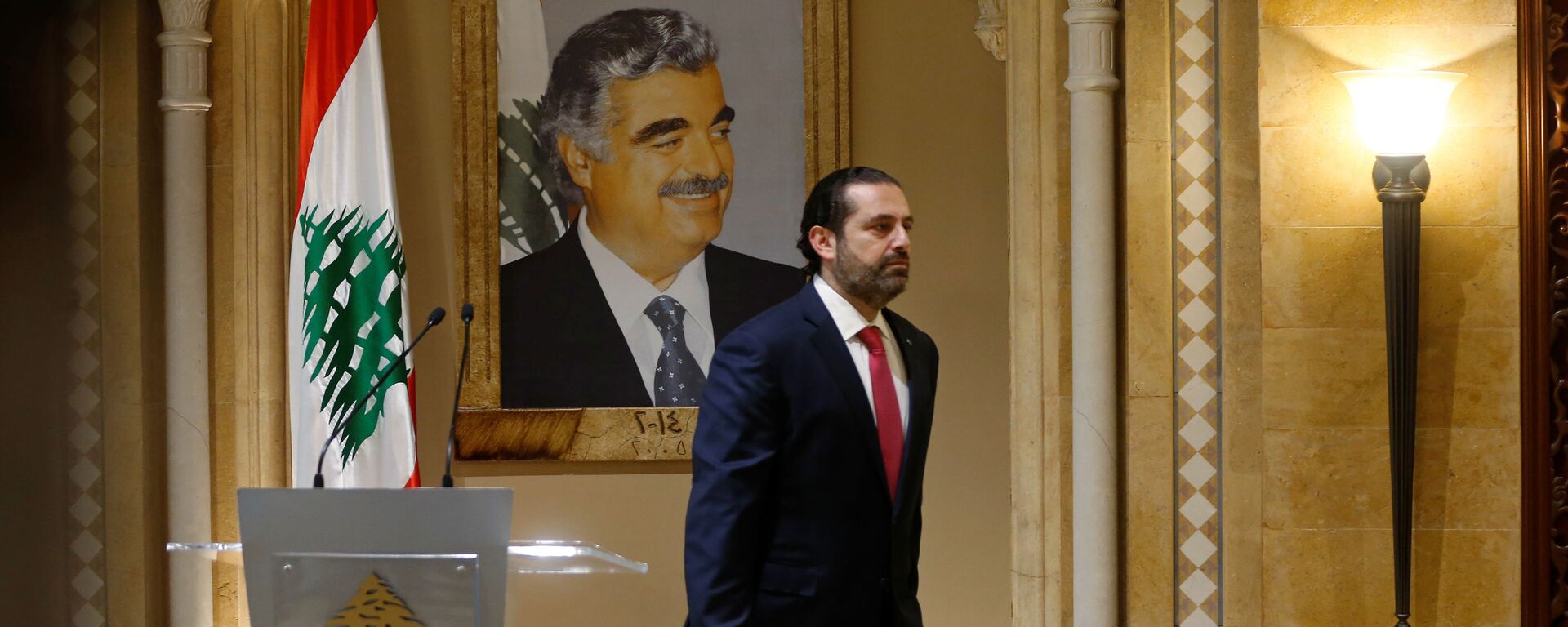 Suikasta kurban giden babası Refik Hariri'nin portresi önünde başbakanlıktan istifasını sunacağını açıklayan Saad Hariri, salondan çıkarken - Sputnik Türkiye, 1920, 30.10.2021