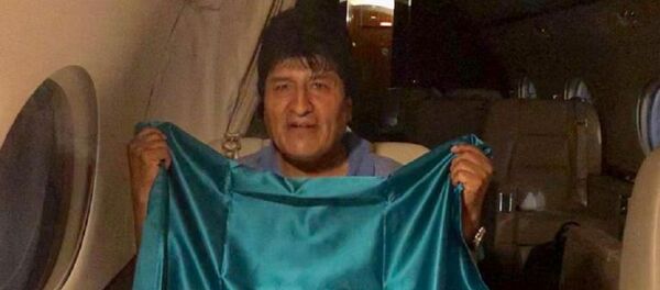 İstifaya zorlanan Bolivya Devlet Başkanı Evo Morales, iltica teklifini kabul ettiği Meksika hükümetinin uçağında ülkenin bayrağını taşırken. - Sputnik Türkiye