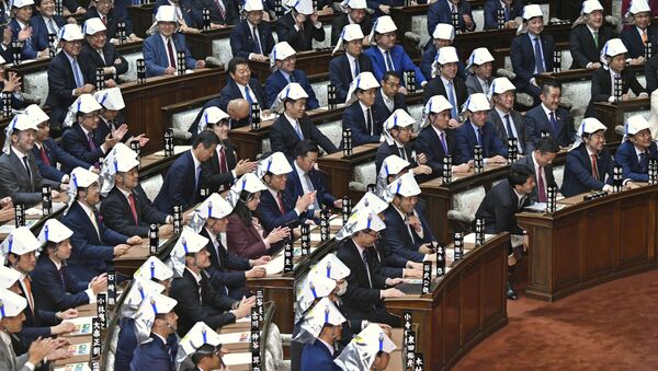 Japonya parlamentosundaki deprem tatbikatında vekillerin başlarını koruma amaçlı taktığı katlanır kaskların tasarımı alay konusu oldu. - Sputnik Türkiye
