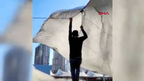 Kadıköy'de pazarcı çadır kurarken ip koptu. Şiddetli, rüzgar nedeniyle havalanan çadırın ipini bırakamayan pazarcı metrelerce yükseldi. O anlar cep telefonu kamerasına yansıdı. - Sputnik Türkiye