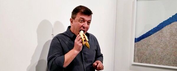 Performans sanatçısı David Datuno, İtalyan sanatçı Maurizio Cattelan’ın 120 bin dolara satılan ‘duvara bantlanmış muz’ çalışmasını yedi. - Sputnik Türkiye