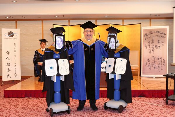 Robotun yüz kısmındaki tablet üzerinde görüntüleri yer alan öğrenciler, mezuniyet elbisesi giydirilmiş robotlar aracılığıyla sırasıyla üniversite yetkililerinden diplomalarını aldı. - Sputnik Türkiye