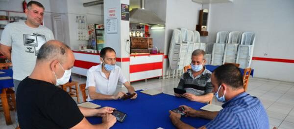 Adana'da okey, tavla, iskambil oynanmaması kaydıyla açılan kahvehaneye gelen vatandaşlar, cep telefonlarındaki uygulamayla mobil okey oynadı. - Sputnik Türkiye
