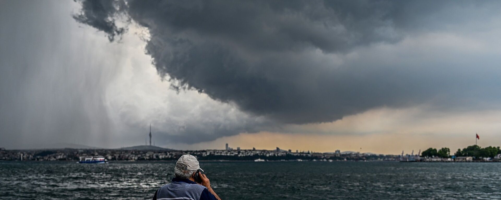 Sağanaktan önce Boğaz'a bakarak telefonla konuşan bir adam - İstanbul - Karaköy - Sputnik Türkiye, 1920, 20.02.2025